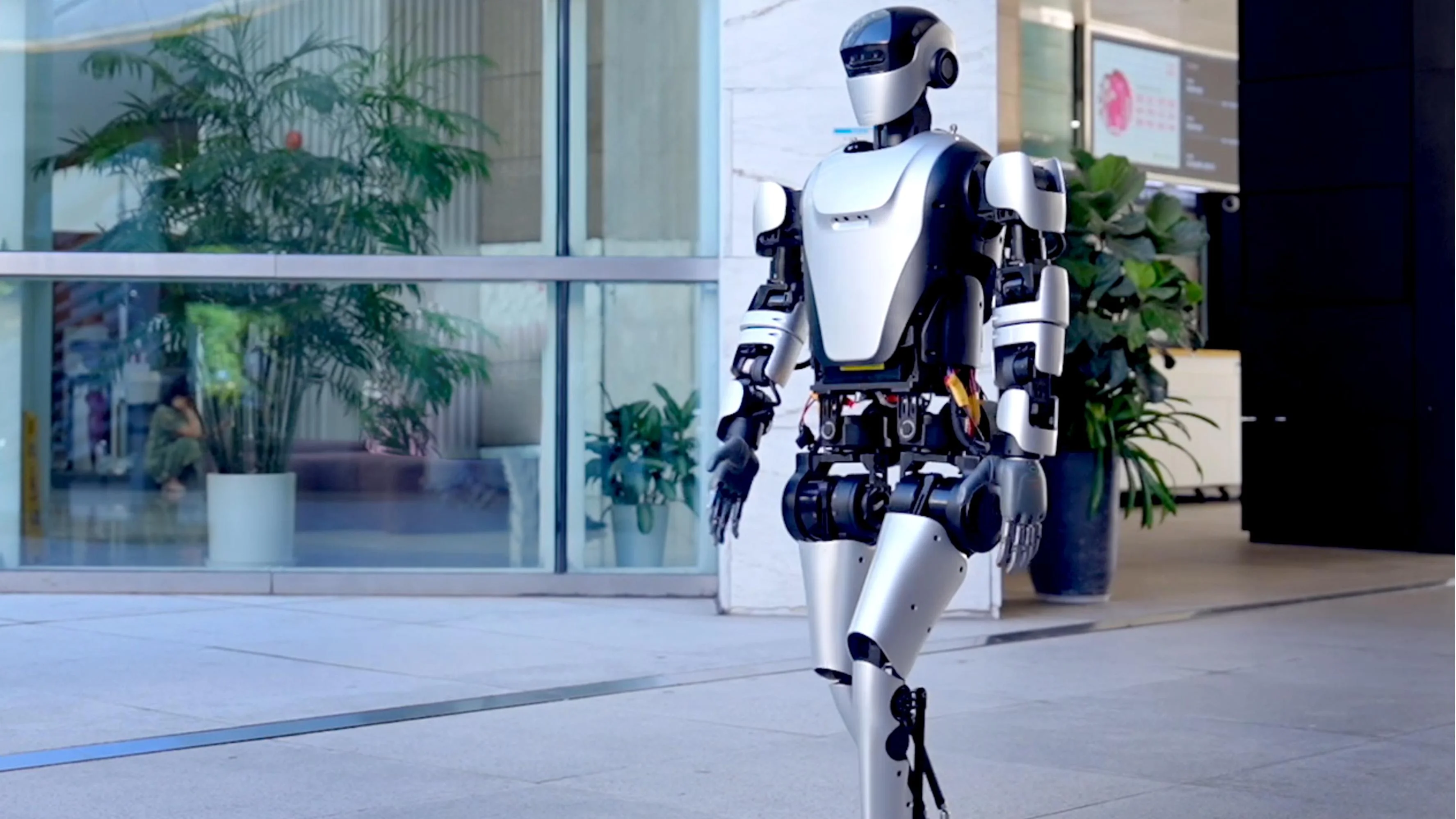 A humanoid robot from Leju Robot is walking in an office space