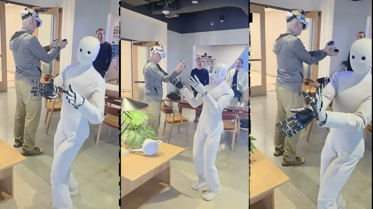 Robotics expert Scott Walter, wearing a VR headset, teleoperates the 1X NEO humanoid robot, which mirrors his arm movements.