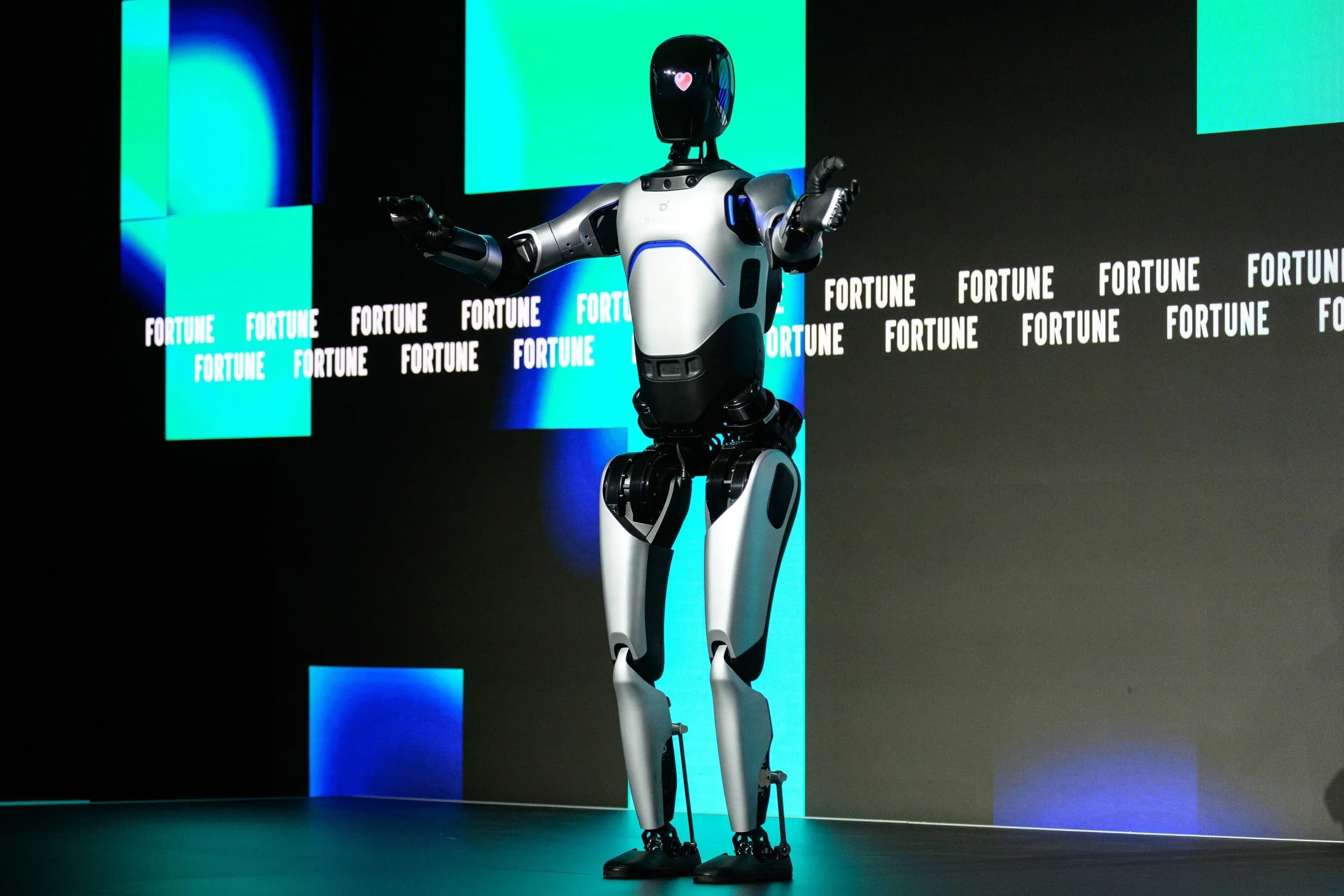 A full-sized AgiBot A2 humanoid robot standing on a stage with a digital background displaying the Fortune logo.