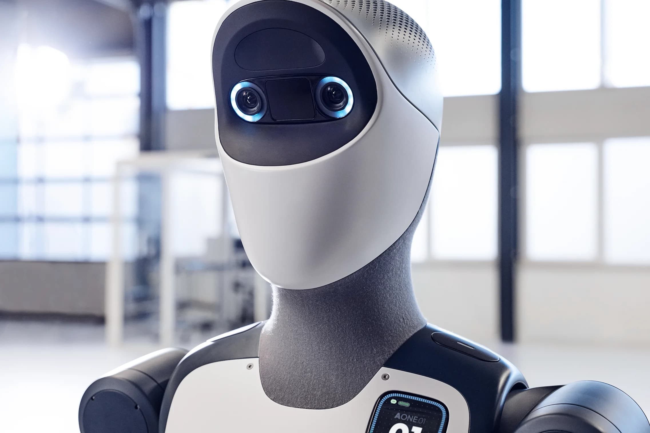 A close-up of the Agile ONE robot's head, showing a smooth white faceplate, two camera lenses surrounded by blue illuminated rings, and a forehead-mounted sensor array.