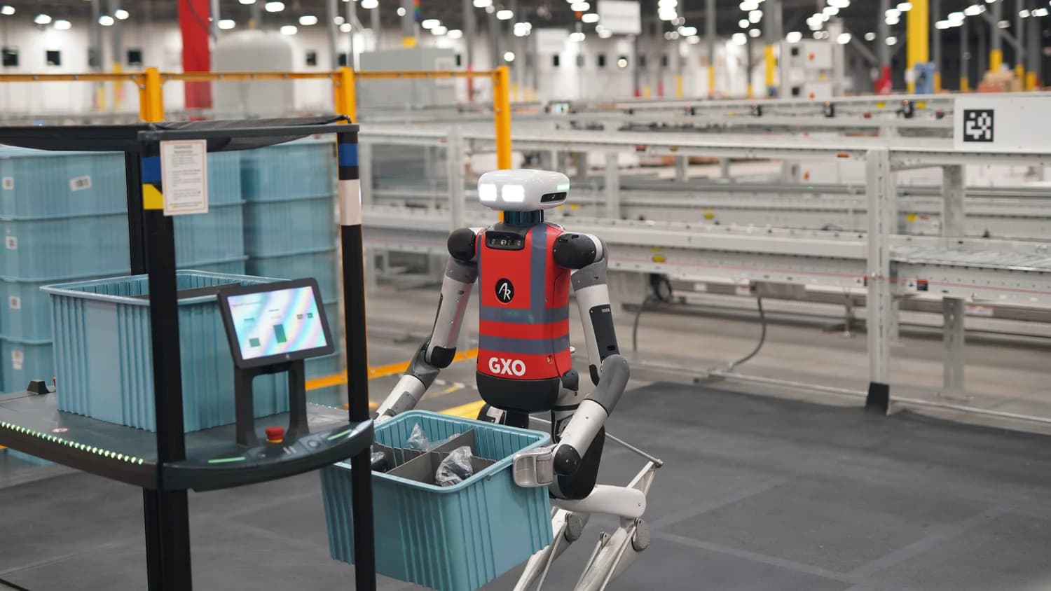 Agility Robotics' Digit robot carrying a blue tote in a GXO warehouse.