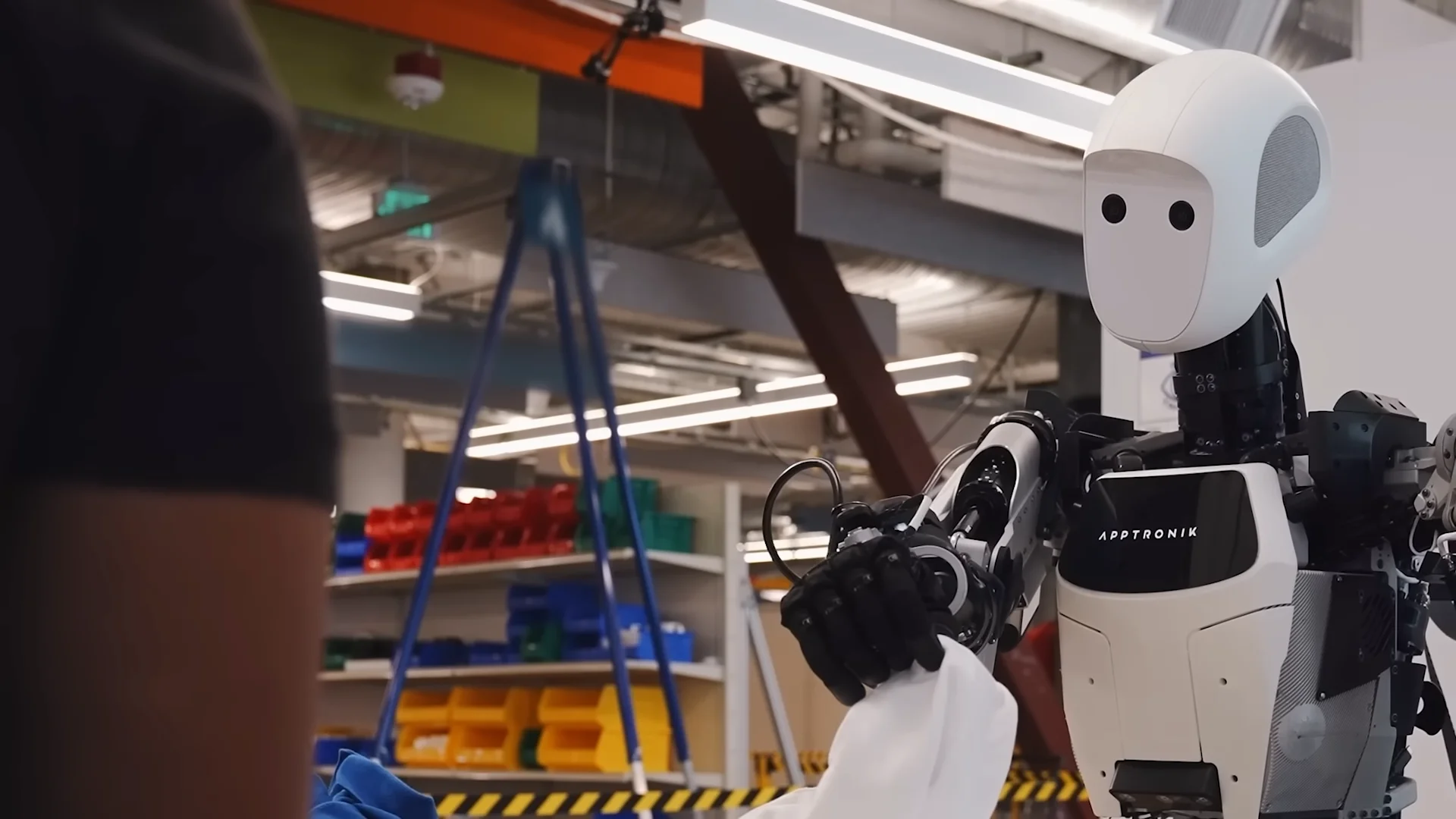The Apptronik Apollo humanoid robot holding a white piece of clothing while performing a laundry sorting task.