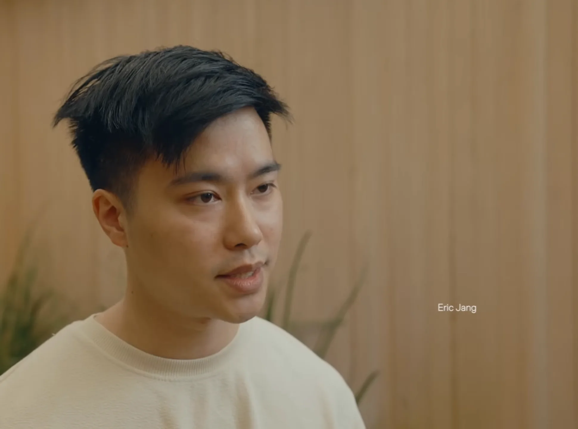 Headshot of Eric Jang, former Vice President of AI at 1X, looking toward the side against a wooden paneled wall.