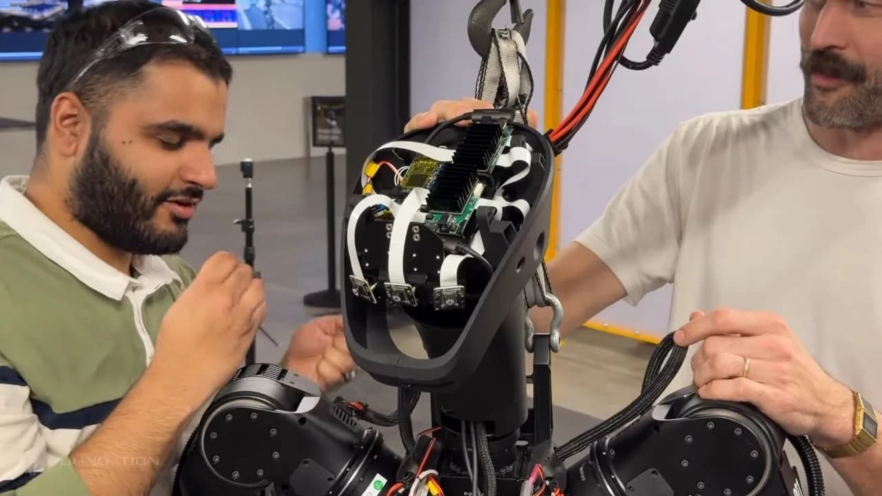 Two technicians at Foundation's San Francisco headquarters manually assemble the Phantom's head. The exposed internal hardware includes a prominent black finned heat sink, white ribbon cables, and multiple camera sensors .