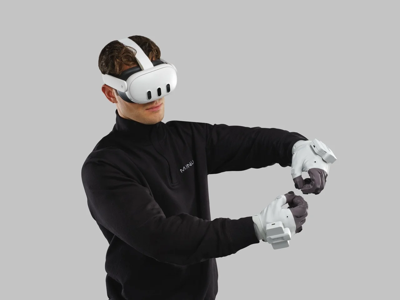 A person wearing a white VR headset and Manus Metagloves Pro Haptic, holding their hands in a precision pinch gesture to demonstrate spatial interaction.