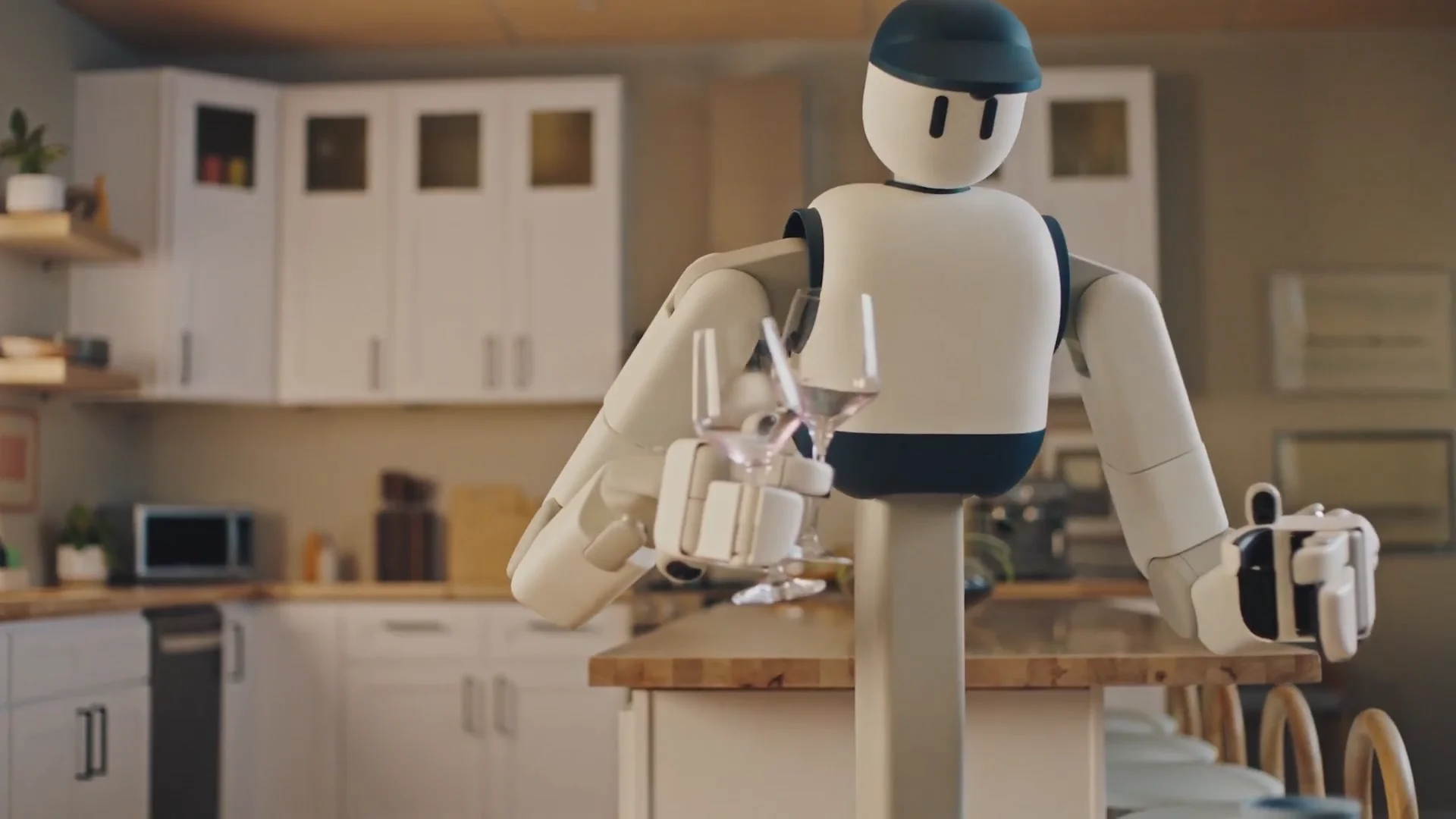 A white Sunday Memo robot with a minimalist face and a blue cap holding two delicate wine glasses in a domestic kitchen setting.