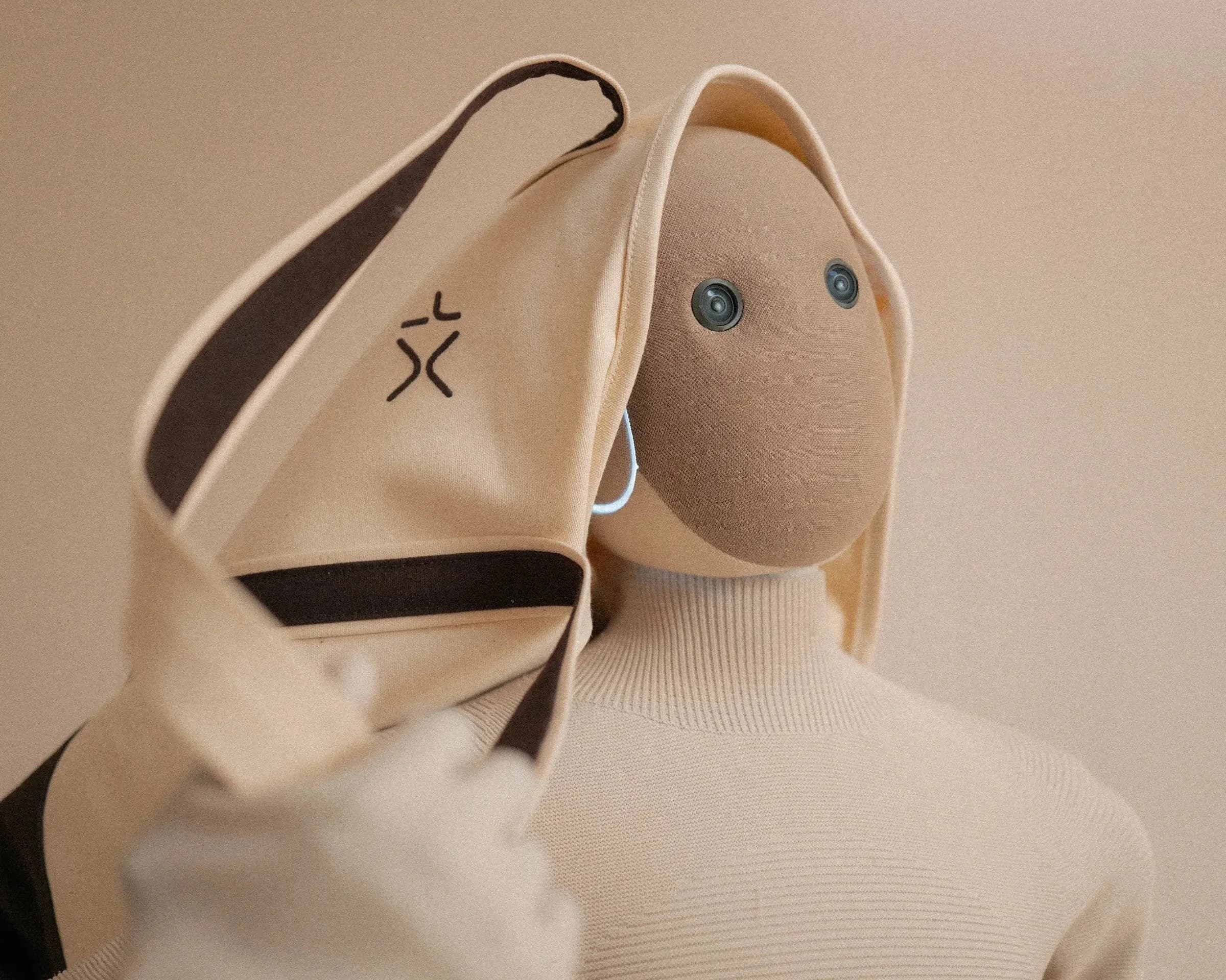 Close-up of the 1X NEO robot holding a beige canvas tote bag over its shoulder, featuring the 1X logo.