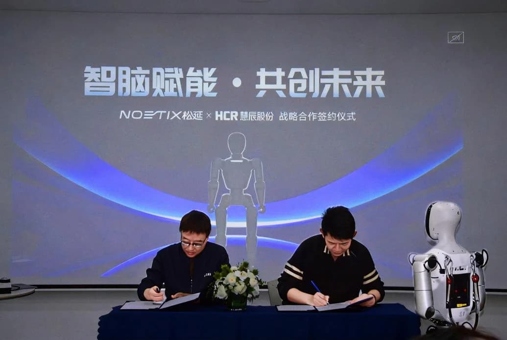 Executives from Noetix Robotics and HCR signing a strategic partnership agreement at a table, with a Bumi humanoid robot standing to the right.