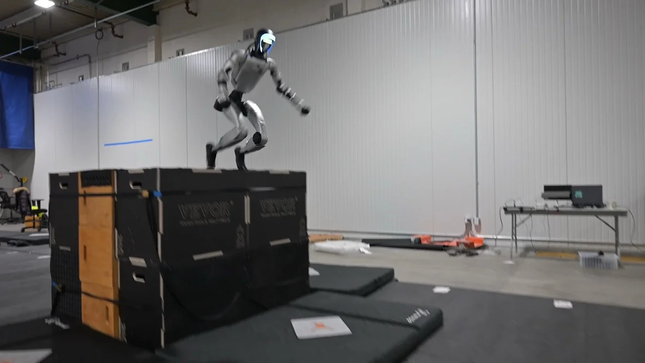 A Unitree G1 humanoid robot standing on a 1.25-meter-tall black platform in a research facility, demonstrating successful wall-climbing capability.