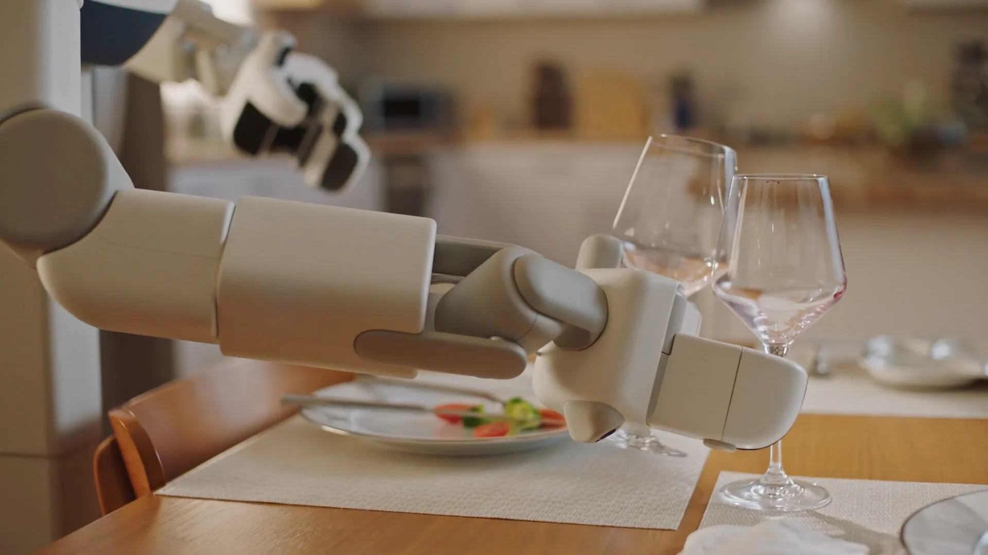 A close-up of Memo's robotic end-effector holding two wine glasses at once, perfectly replicating the multi-object grasp demonstrated by the human operator.