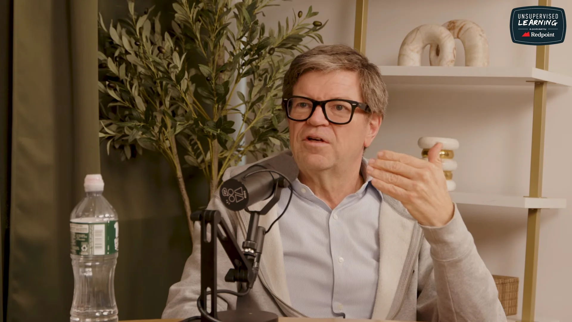 Yann LeCun speaking into a studio microphone, gesturing with his hand during an interview on the Unsupervised Learning podcast.